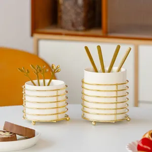 Ceramic tableware storage jar set with gold metal wire frame and spoons for desktop.