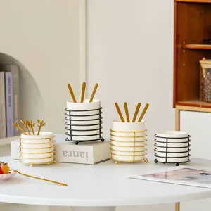 Minimalist ceramic tableware storage jar set with metal wire rack and golden spoons for desk.