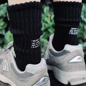 Detail shot of black knitted crew socks with white text print, showcasing cityboy fashion style.