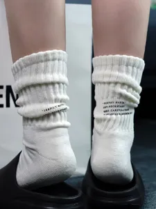 Detailed view of white stacked socks with printed text and ribbed design, cozy and stylish.