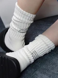 Detail view of heavy knit white socks with printed text, thick towel bottom and stacked fit.