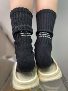 Detailed close-up view of black ribbed crew socks with knit lettering and streetwear tooling style.