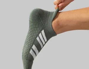 Close-up detail of green athletic short socks with white stripes showing ankle wear.