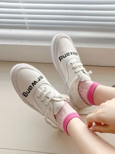 Detailed view of white canvas shoes paired with pink contrast mesh socks for a sweet style.