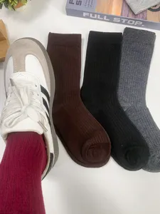 Vue rapprochée de chaussettes montantes côtelées bordeaux, noires et grises bien arrangées.