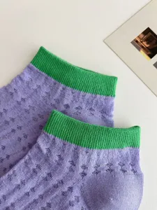 Detail shot of purple mesh hollow-out socks with green ribbed cuffs for sweet summer style.