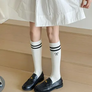 Close-up detail of white knee-high socks with double stripes and cute bow embroidery.