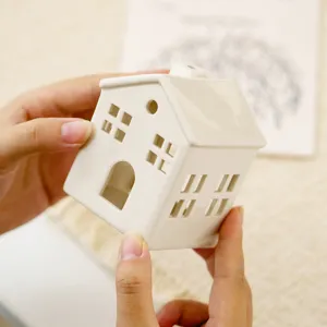 White ceramic house candle holder, hollow tealight lantern for home decor and holiday table.