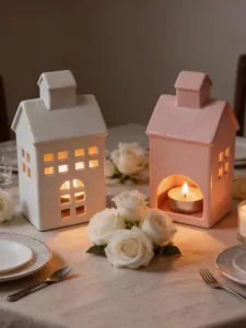 Vue detaillee de bougeoirs de maison en ceramique blanche et rose avec des roses sur la table.