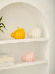 Ceramic pumpkin figurine detail, modern minimalist home decor ornament on white shelf scene.