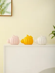 Detailed view of ceramic pumpkin home decor ornaments in pink, yellow and white colors.