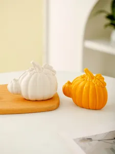 Detailed close-up of modern ceramic pumpkin ornament, tabletop home decor in white and yellow.