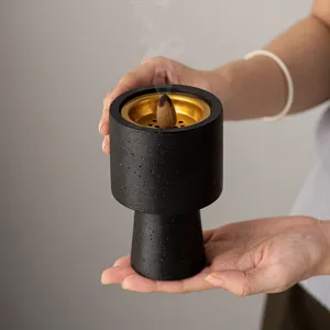 Handheld backflow incense burner with gold interior, modern black home decor fragrance piece.