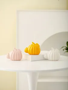 Ceramic pumpkin figurine detail, modern desktop decoration in pink yellow and white colors.