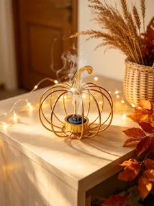 Detailaufnahme des goldenen Metall Kürbis Rauchfässchens für moderne Aromatherapie am Tisch.