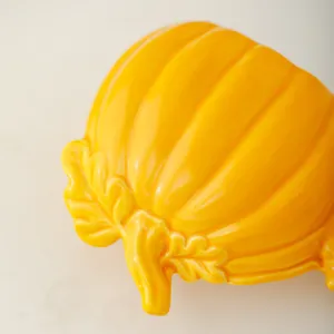 Ceramic pumpkin decor detail shot, vibrant yellow gloss finish, elegant leaf stem.