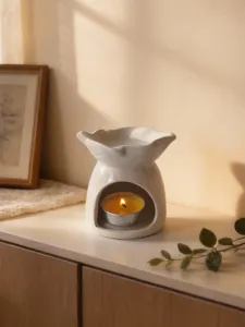 Dettaglio del portacandele in ceramica bianca a cuore con lumino su tavolo in legno.