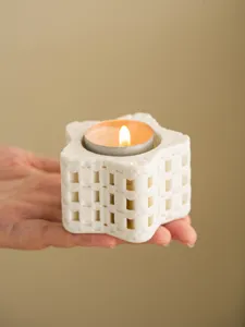 Nahaufnahme eines weissen 3d gedruckten Stern Teelicht Halters mit brennender Kerze.
