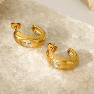 Primer plano de pendientes en forma de C de acero de titanio chapado en oro de 18K.