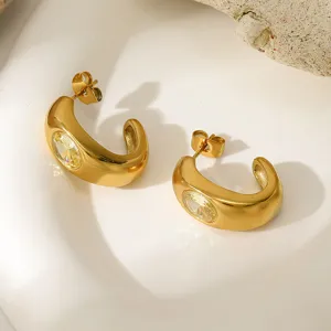 Primer plano de pendientes de aro dorados gruesos en forma de C con cristal amarillo.