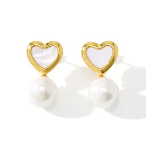 Gold heart-shaped pearl earrings detail shot showcasing delicate metallic luster and classic design.