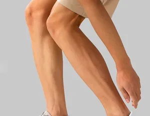 Detail view of athletic wear showing leg and shoe styling, clean neutral studio background.