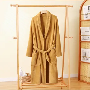 Close-up van zachte okergele koraal fleece badjas hangend aan een rek in warme sfeer.