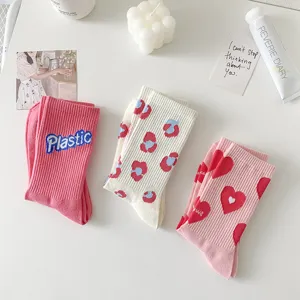 Detail view of cute pink and white cotton crew socks with sweet heart and pattern designs.