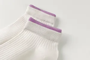 Close-up detail of women white short socks featuring purple ribbed cuffs breathable design