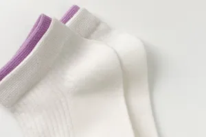Close-up detail of white women short socks with purple ribbed cuffs, breathable cotton fabric.