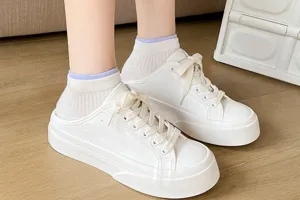 Close-up shot of white short socks and platform canvas shoes worn on feet, stylish casual detail.