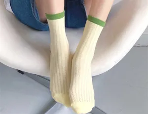 Close-up view of breathable mesh mid-tube socks featuring green ribbed cuffs and yellow body.