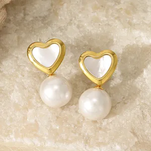 Close-up detail of retro gold heart faux pearl drop earrings on raw crystal stone background.