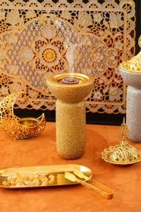 Dettaglio di un bruciaincensi in resina glitterata dorata per fragranze d'ambiente orientali.