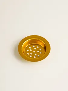Close-up of a gold-colored metal incense burner strainer gasket with hollow mesh holes.
