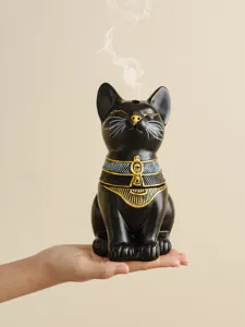 Closeup of Egyptian cat incense burner detail showing golden and white painted patterns.