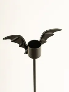Vue détaillée du bougeoir en fer noir avec ailes de chauve-souris pour déco de table.