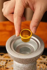 Vista dettagliata del bruciatore di incenso in resina con tazza dorata e base glitterata.