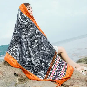 Detail view of the ethnic style beach towel scarf with black white paisley print and orange border.