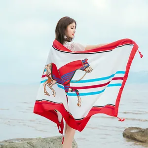 Detail view of the elegant beach scarf with horse print and tassels in outdoor setting.