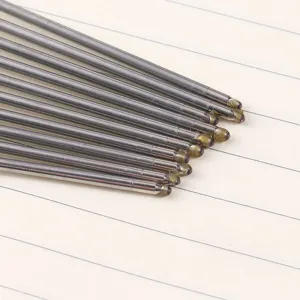 Close-up detail of metal ballpoint pen refill tips neatly arranged on lined paper.