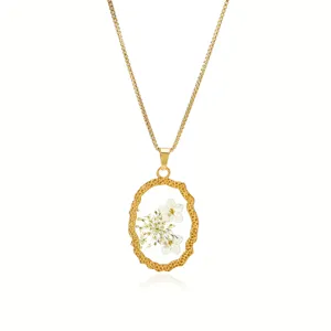 Primer plano del collar vintage de acero de titanio con colgante de resina y flor seca.