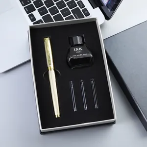 Close-up van gouden gegraveerde vulpen cadeaupakket met inktfles en patronen op bureau.