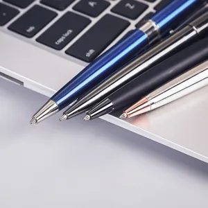 Close-up detail shot of assorted metal ballpoint pens in multiple colors on laptop.