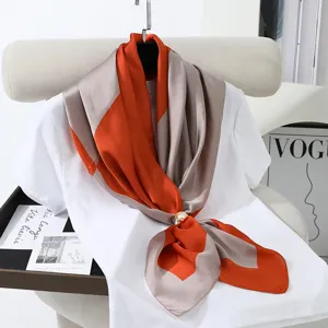 Detail view of a 90cm satin square scarf with chic geometric color blocks and a pearl buckle.