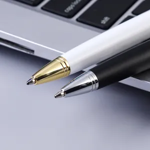 Close-up detail of luxury metal ballpoint pens with white and black barrels on a desk.