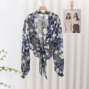Close-up detail of a blue floral chiffon tie-front shrug cardigan with long sleeves.