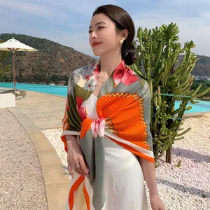 Detailed view of a fashionable floral and chain print square silk scarf worn by model.
