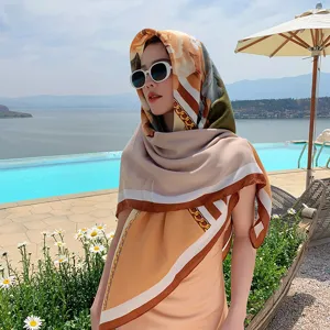 Detailed view of a 130cm floral and chain print square scarf styled as a chic resort headwrap.