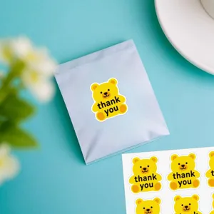 Vue détaillée de jolis autocollants ours jaune merci, parfaits pour emballage cadeau.